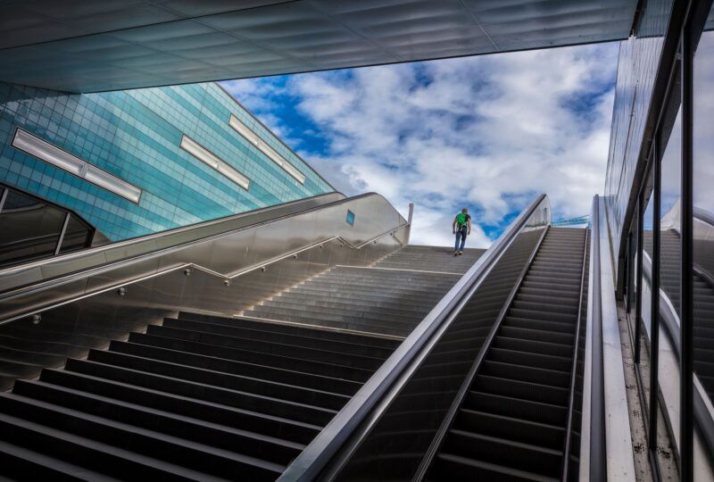 Zwei Fahrtreppen jeweils links und rechts einer regulären Treppe.
