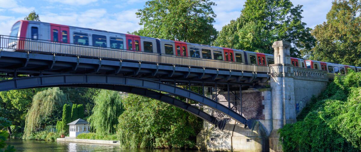 Foto einer U-Bahn bei blauem Himmel, die über eine Brücke fährt