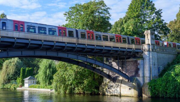 Foto einer U-Bahn bei blauem Himmel, die über eine Brücke fährt